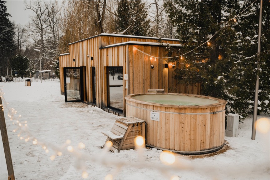 A warm-lit wooden house in the Danish countryside at dawn, snow-dusted trees in the distance.
